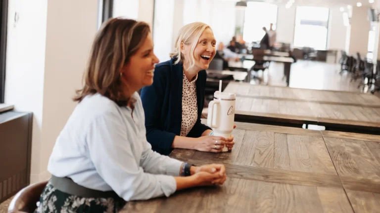 Two women sitting at a table smiling